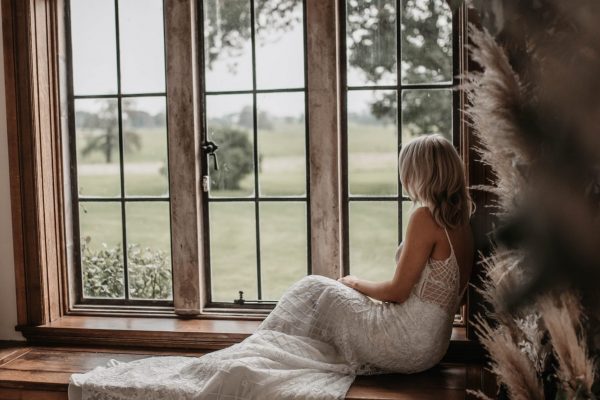 A bride looking out a window on to the private estate